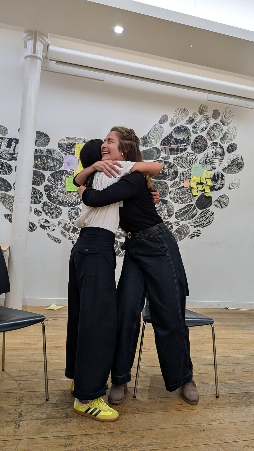 Milly hugging an attendee at an event, both laughing