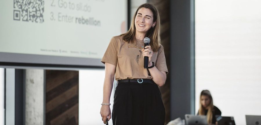 Milly mid-sentence with a microphone, smiling