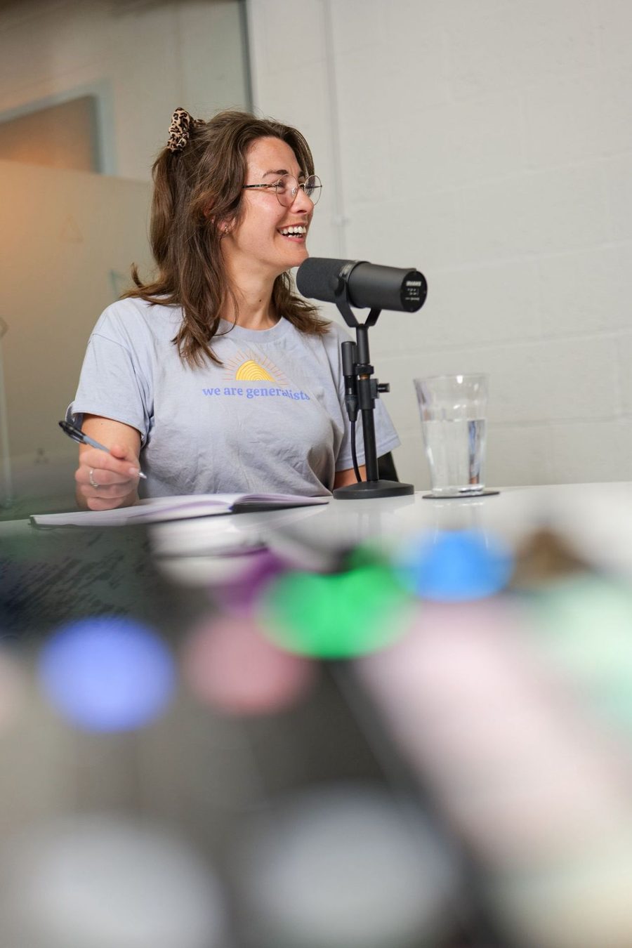 Milly recording the podcast at a microphone, mid-laugh